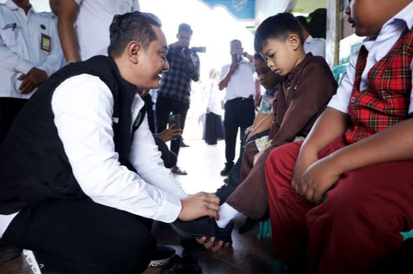 Foto: Wakil bupati Lumajang, Yudha Adji Kusuma (Mas Yudha) nerikan langsung bantuan sepatu kepada murid SDN Randuagung 01